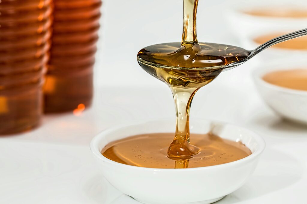 Clear sugar syrup pouring onto spoon, produced using invertase and dextranase enzymes for improved clarity and purity in sugar processing